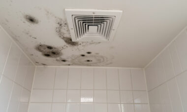 Plafond de salle de bains présentant des taches de moisissure et de la condensation près d’une bouche d’aération.