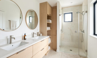 Salle de bain familiale lumineuse avec double vasque, rangements intégrés, douche vitrée et accessoires sobres.