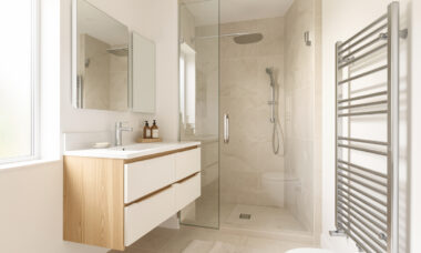 Salle de bain moderne et lumineuse avec meuble vasque, douche vitrée, rangements intégrés et sèche-serviettes contemporain.