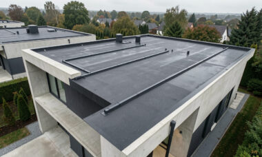 Vue aérienne d’une maison moderne à toit plat, avec une évacuation d’eau propre et des surfaces soigneusement entretenues.